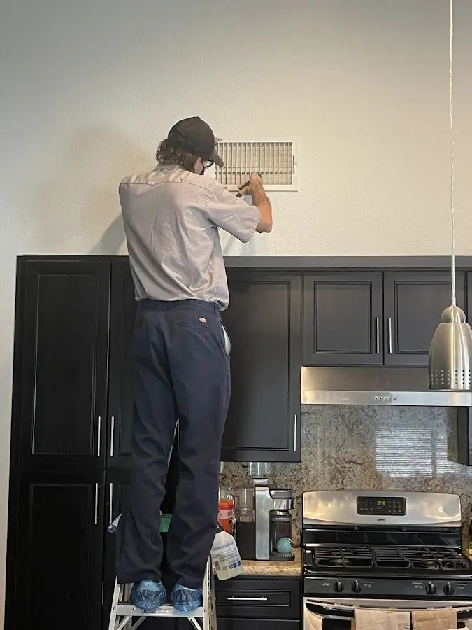 Technician inspecting an air vent during HVAC service in Batesville